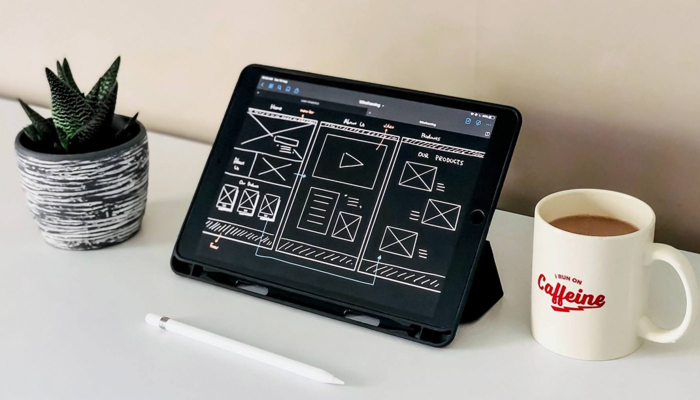 Tablet displaying a digital sketch of a website design, featuring a plant as part of the layout.